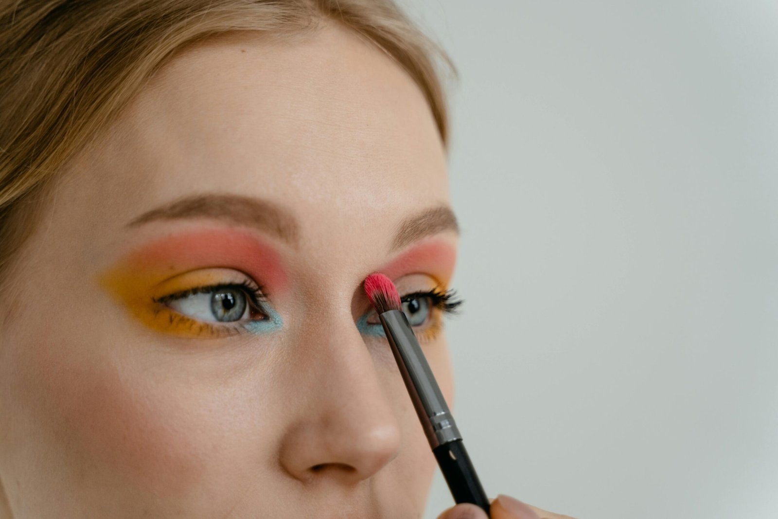 Home Vibrant eyeshadow application close-up with makeup brush on woman's eyelid.